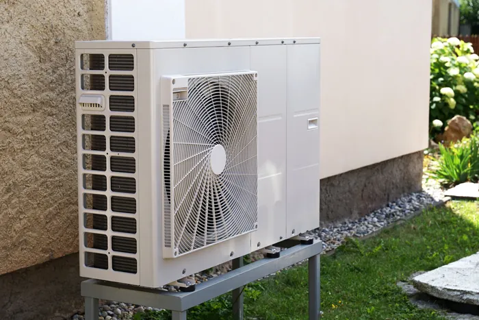 A high-efficiency outdoor heat pump unit installed on a stand beside a home
