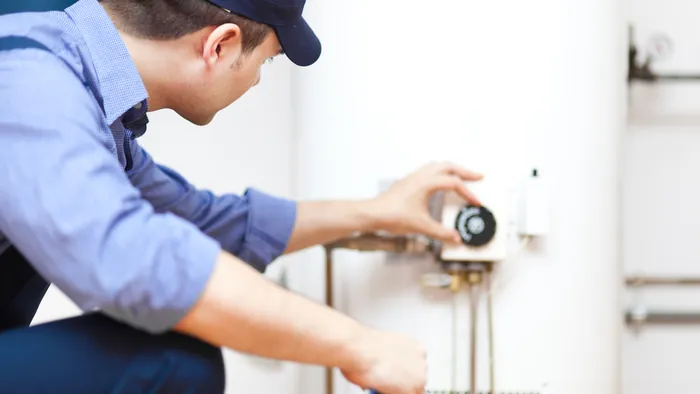 A technician adjusting the gas control on a tank water heater